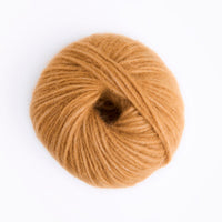 A single ball of warm camel-colored yarn photographed from above on a clean white background.