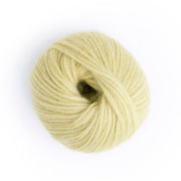 A ball of pale yellow yarn photographed from above on a clean white background.
