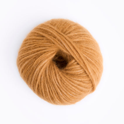 A single ball of warm camel-colored yarn photographed from above on a clean white background.